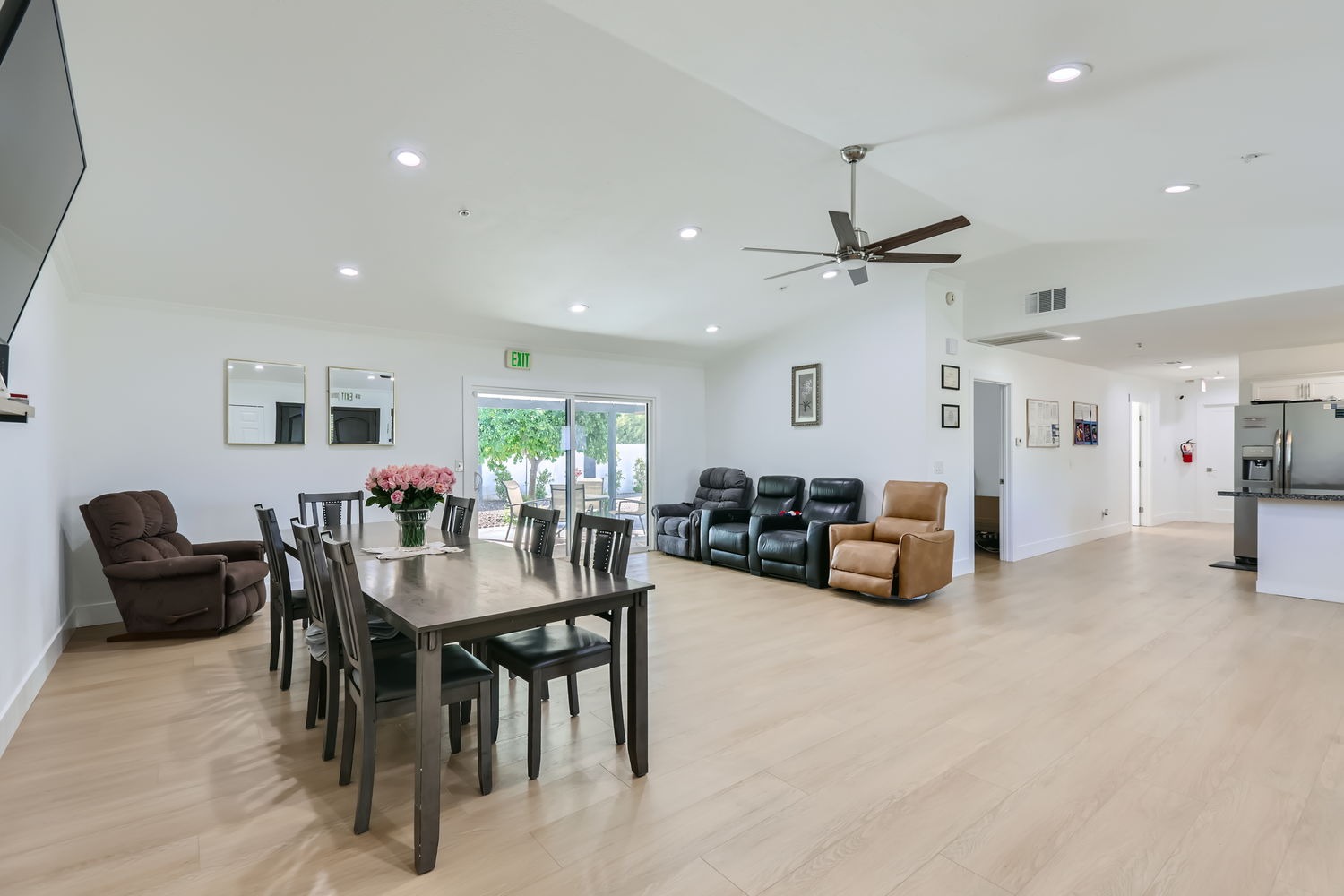 Spacious living room at Senior Valley Assisted Living with a dining table, reclining chairs, and large windows providing natural light.